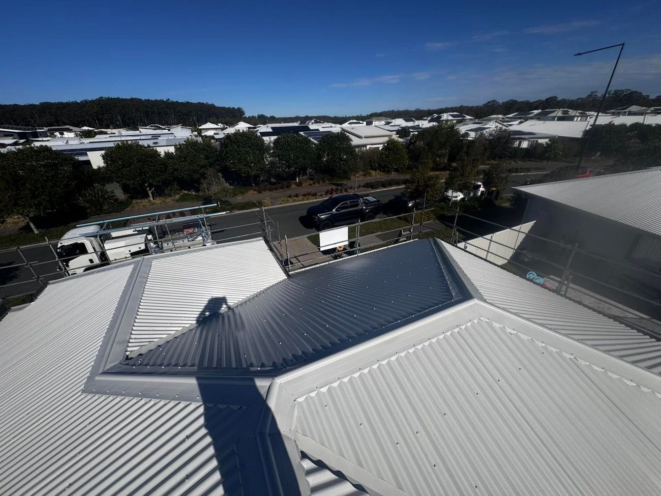 Overhead View of a Shiny, Corrugated Metal Roof With a Street — Rumara Roofing in Sunshine Coast, QLD