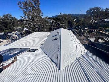 White Corrugated Metal Roof of a Building Under a Bright Blue Sky — Rumara Roofing in Sunshine Coast, QLD