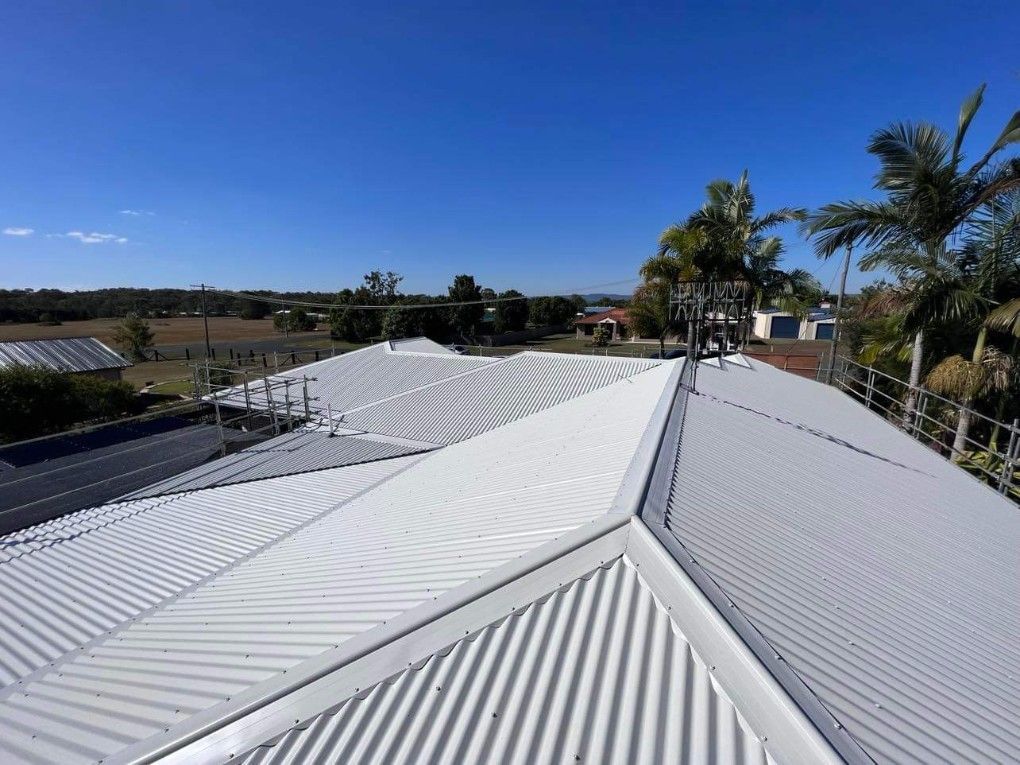 White Corrugated Metal Roof on a Sunny Day; View of the Sky and Distant Buildings — Rumara Roofing in Gympie, QLD