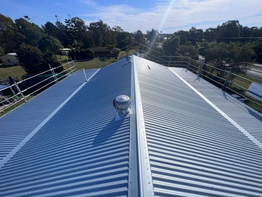 A Corrugated Metal Roof With a Ventilation Cap on a Sunny Day — Rumara Roofing in Maryborough, QLD