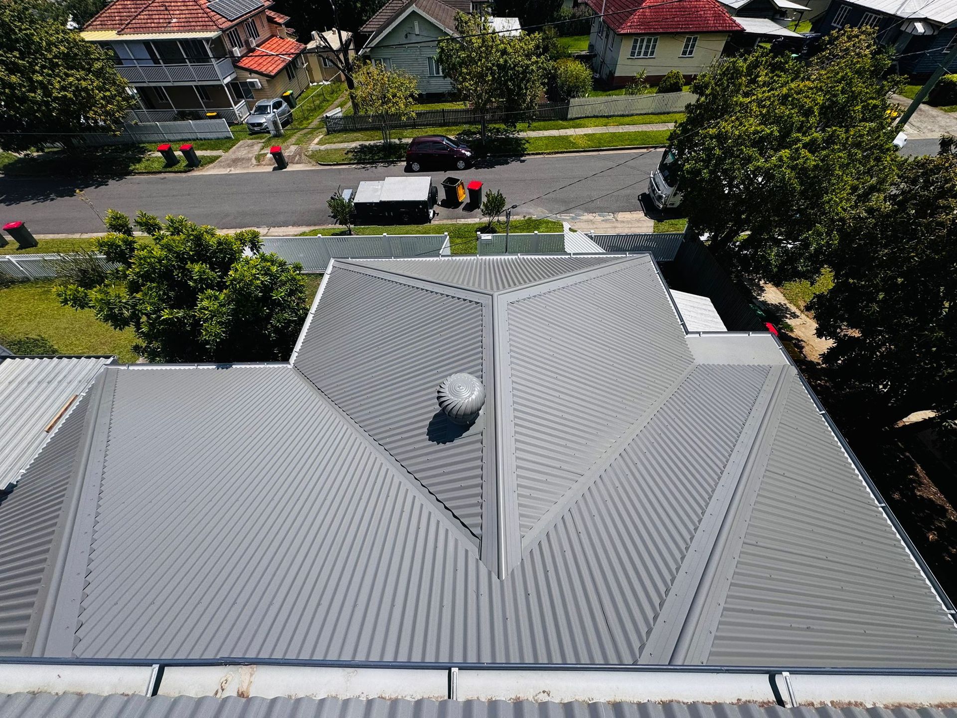Gray metal roof on a house, aerial view. Street and houses in the background — Rumara Roofing in Sunshine Coast, QLD