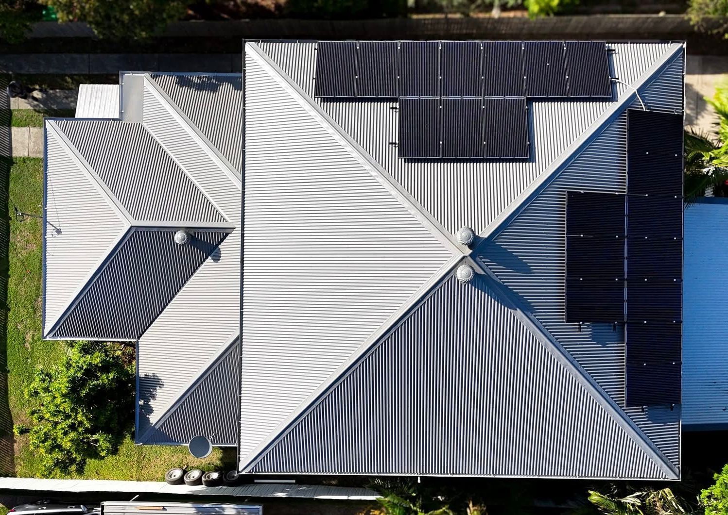 Aerial view of a house with solar panels on a corrugated metal roof — Rumara Roofing in Sunshine Coast, QLD