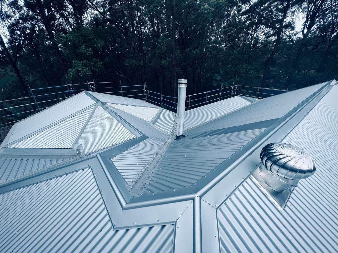 A Metal Roof With a Chimney and Vent, Set Against a Backdrop of Green Trees — Rumara Roofing in Sunshine Coast, QLD