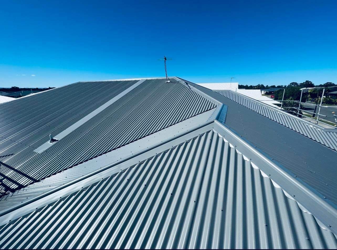 A Grey Corrugated Metal Roof Under a Bright Blue Sky — Rumara Roofing in Sunshine Coast, QLD