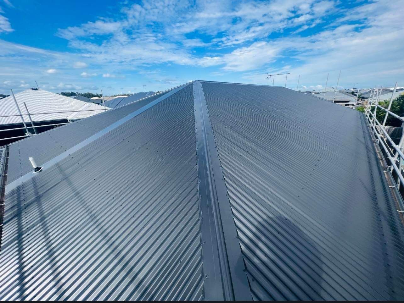 Gray Corrugated Metal Roof With Ridgeline Against a Blue Sky — Rumara Roofing in Sunshine Coast, QLD