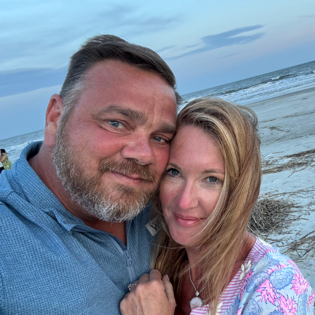 Man and woman smiling together on a beach at dusk.