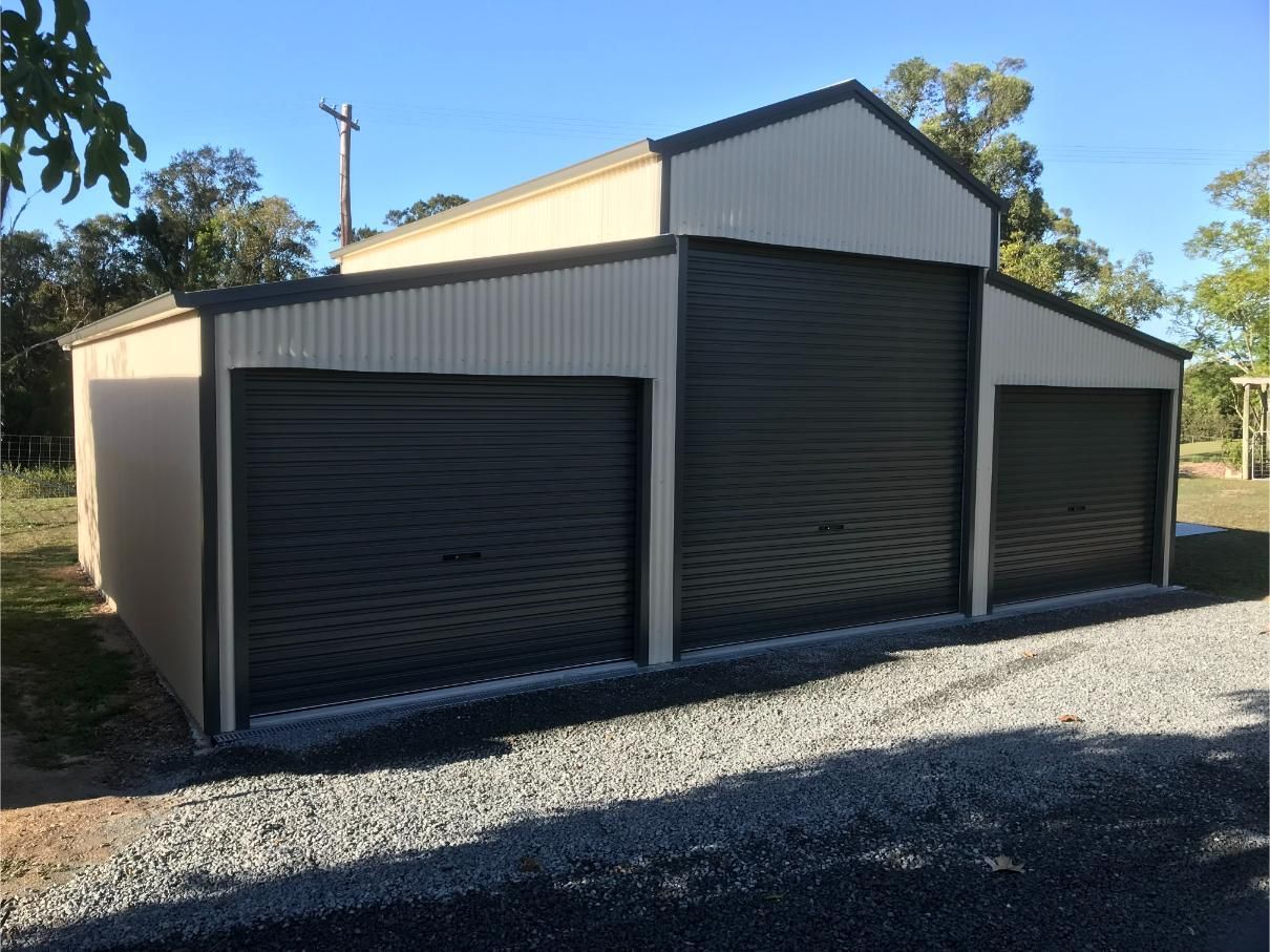 A Large, Beige and Dark Grey Metal Shed With Three Garage Doors — Bridgey's Constructions in Wallabi Point, NSW