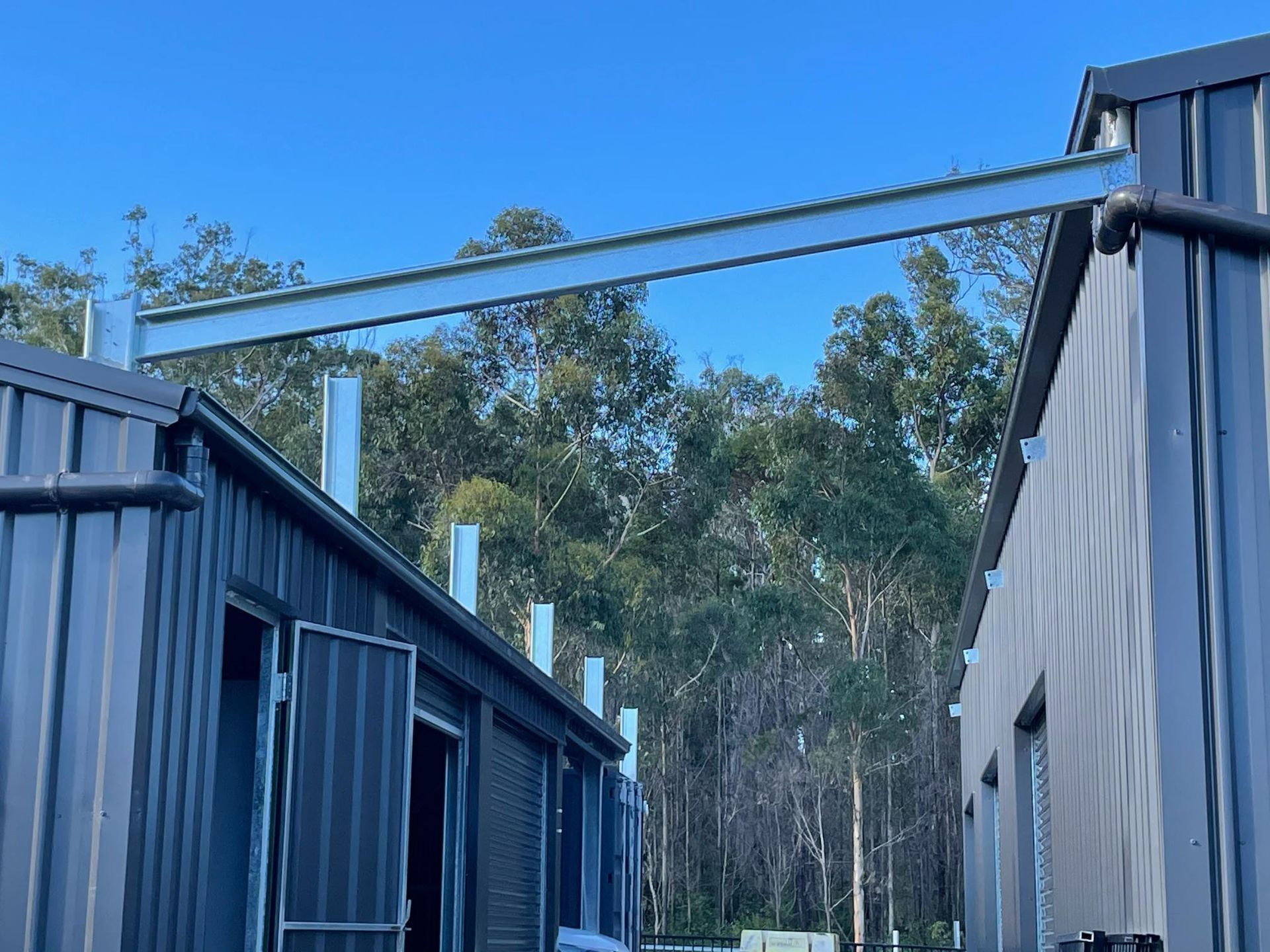 Construction site with two gray buildings connected by a large metal beam in Nabiac, NSW. 