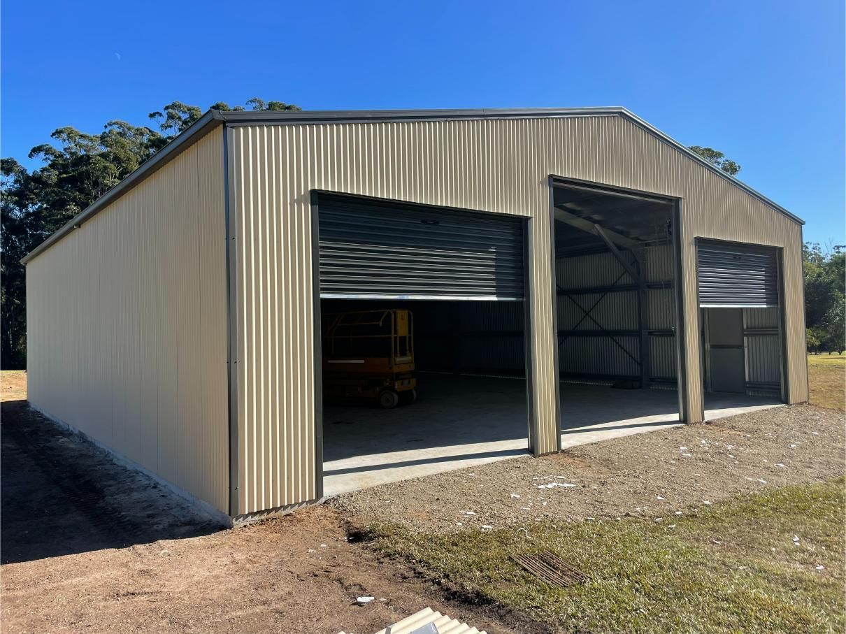 A Tan Metal Shed With Two Open Garage Doors — Bridgey's Constructions in Forster, NSW