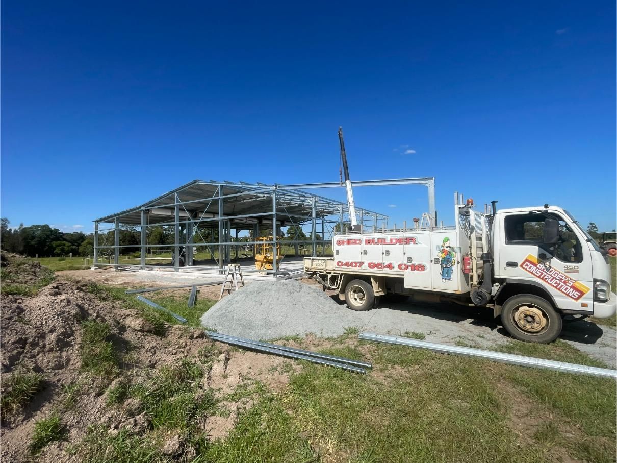 White Utility Truck at A Construction Site Beside a Steel Building Frame — Bridgey's Constructions in Wallabi Point, NSW