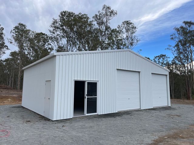 White Corrugated Metal Shed with Open Doorway and Roll Up Door — Bridgey's Constructions in Wallabi Point, NSW