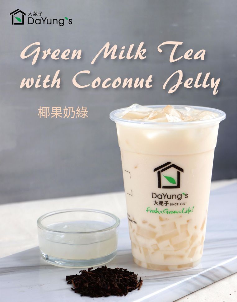 Iced green milk tea with coconut jelly in a clear cup, with a small bowl of jelly and loose tea leaves beside it.