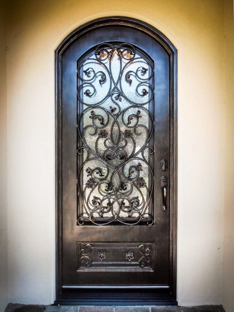A wrought iron door with a glass window on a stone wall
