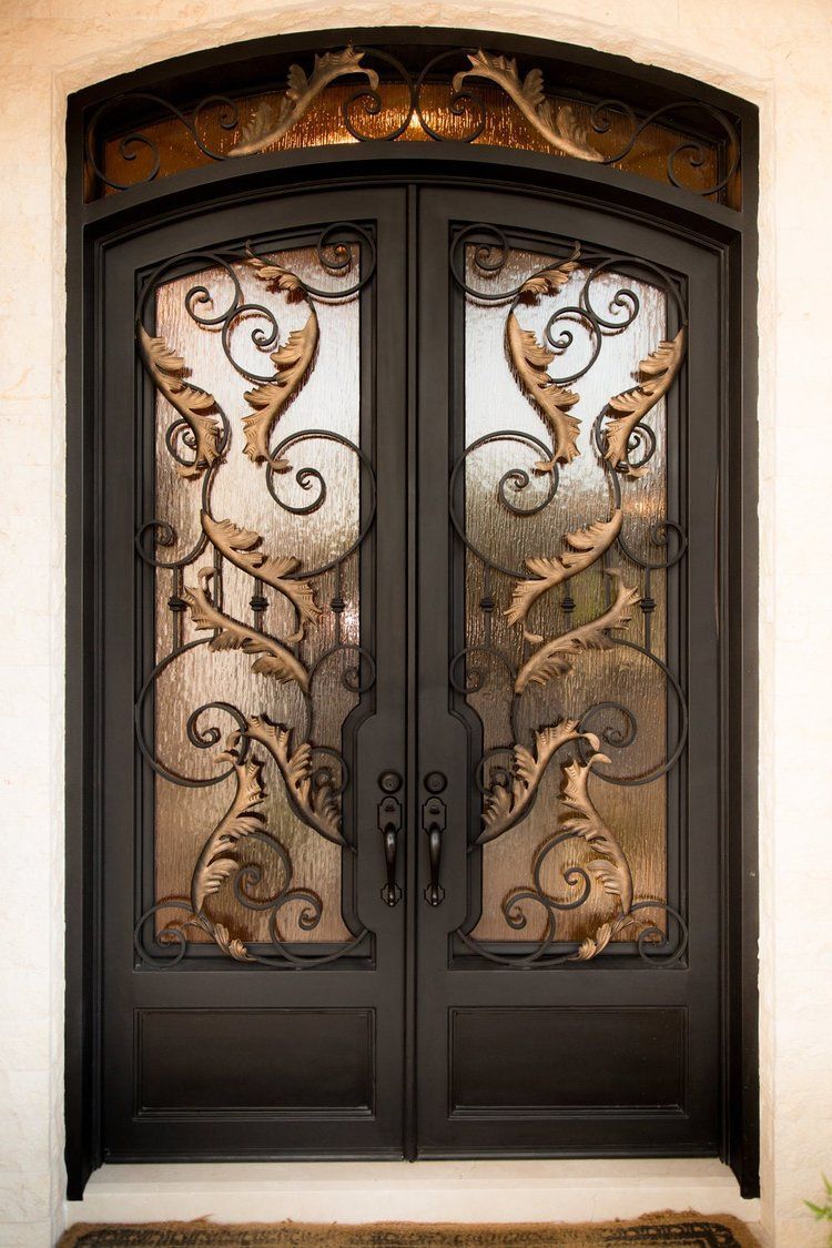 A close up of a wrought iron door on a white wall.