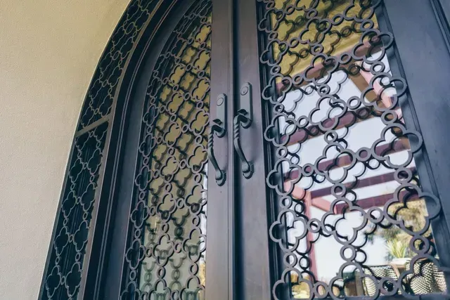 A close up of a wrought iron door with a pattern on it.