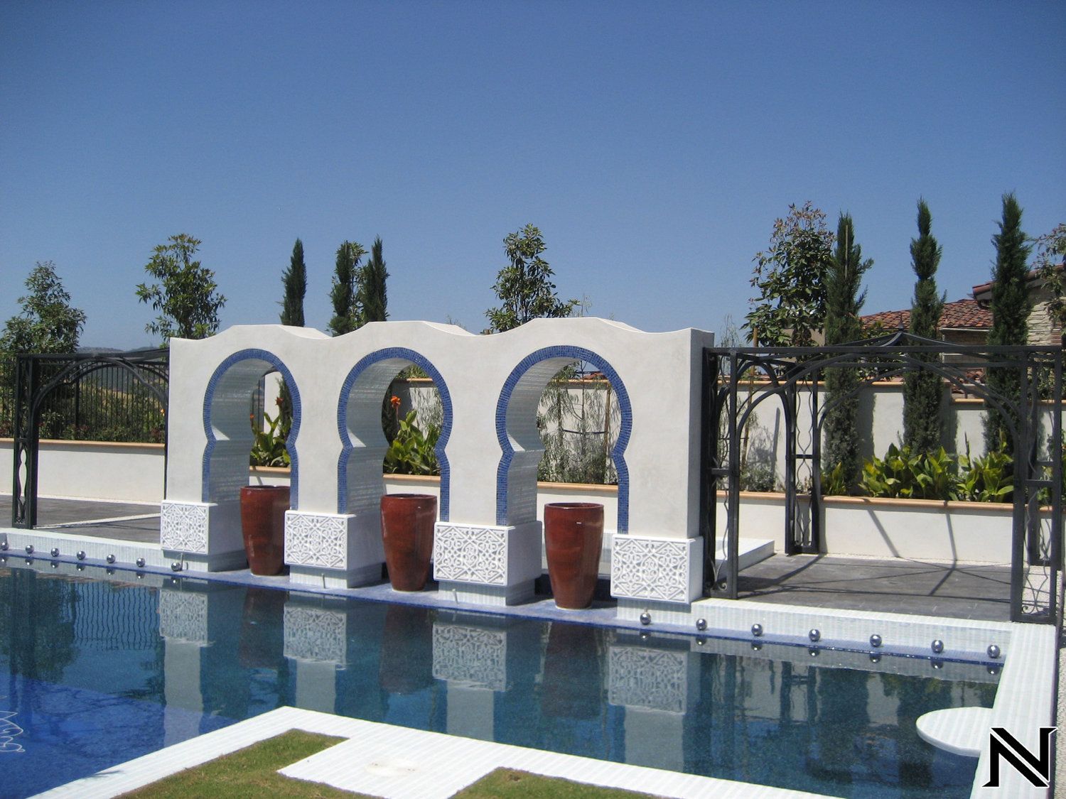 A swimming pool with a fence and arches surrounding it
