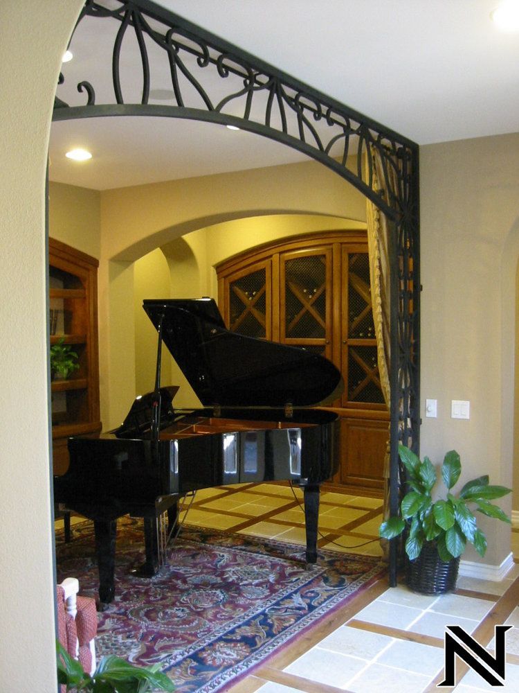 A room with a piano and a plant with the letter n on the floor