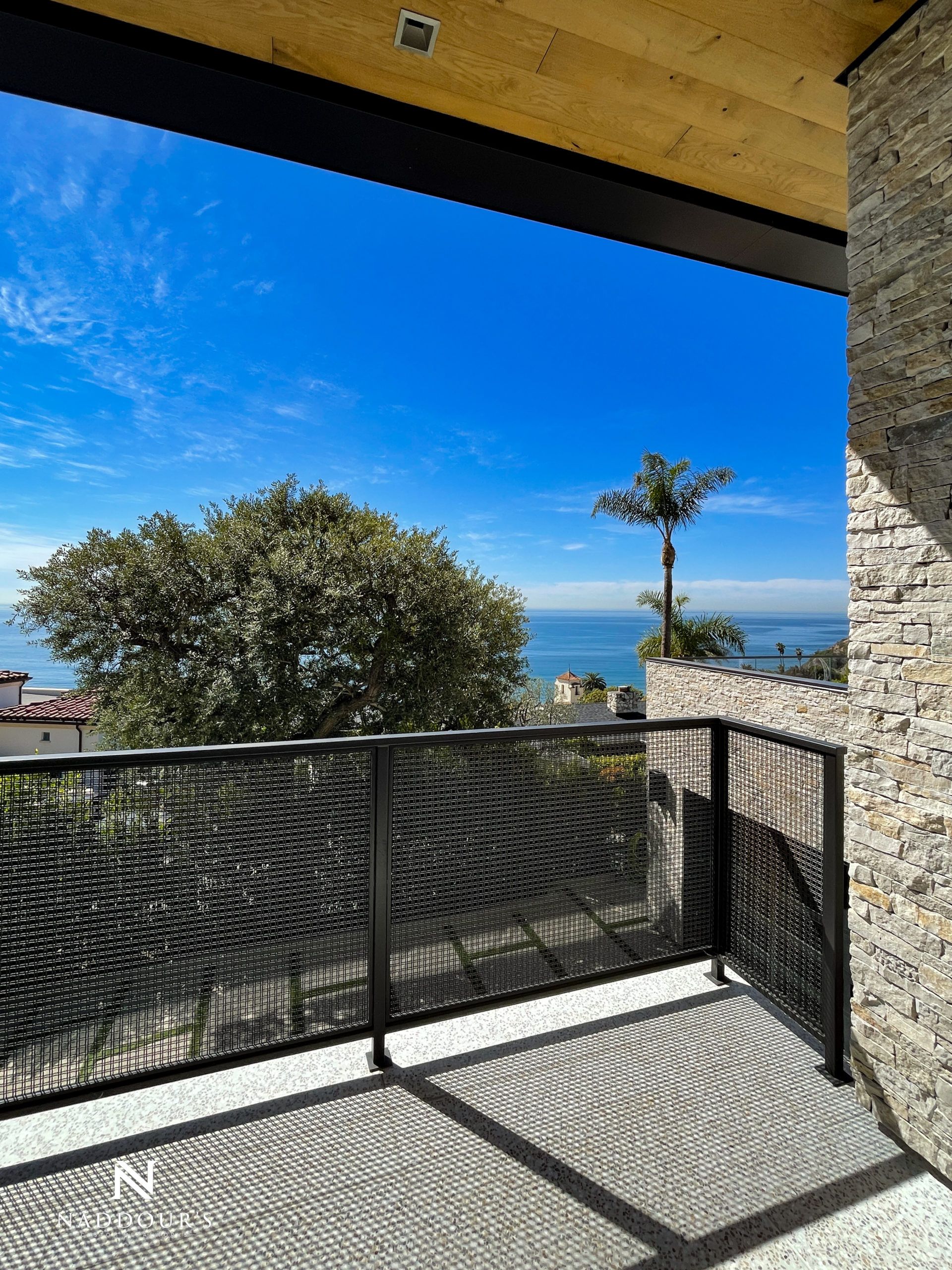 A balcony with a view of the ocean and trees.