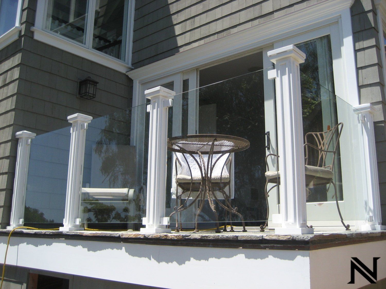 A balcony with a glass railing and a table and chairs