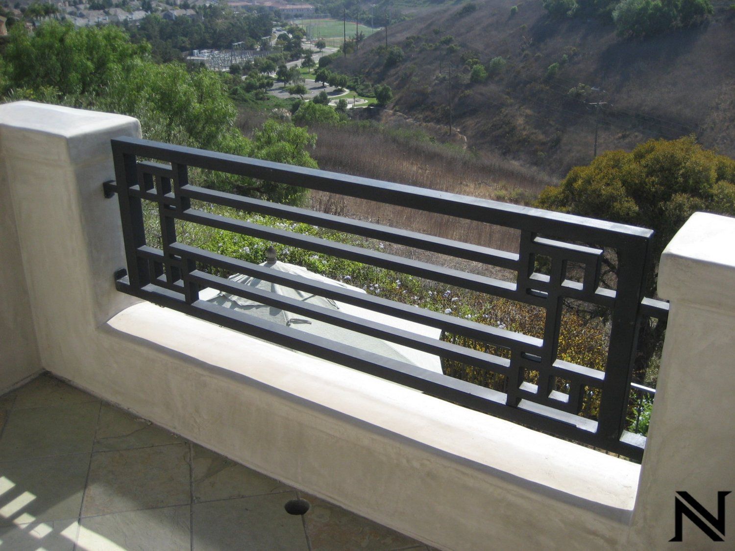 A balcony with a black railing and the letter n on the bottom