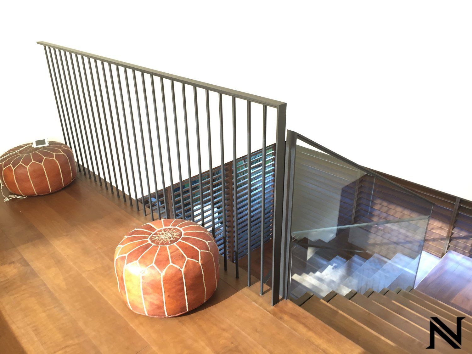 A staircase with a railing and two ottomans on it