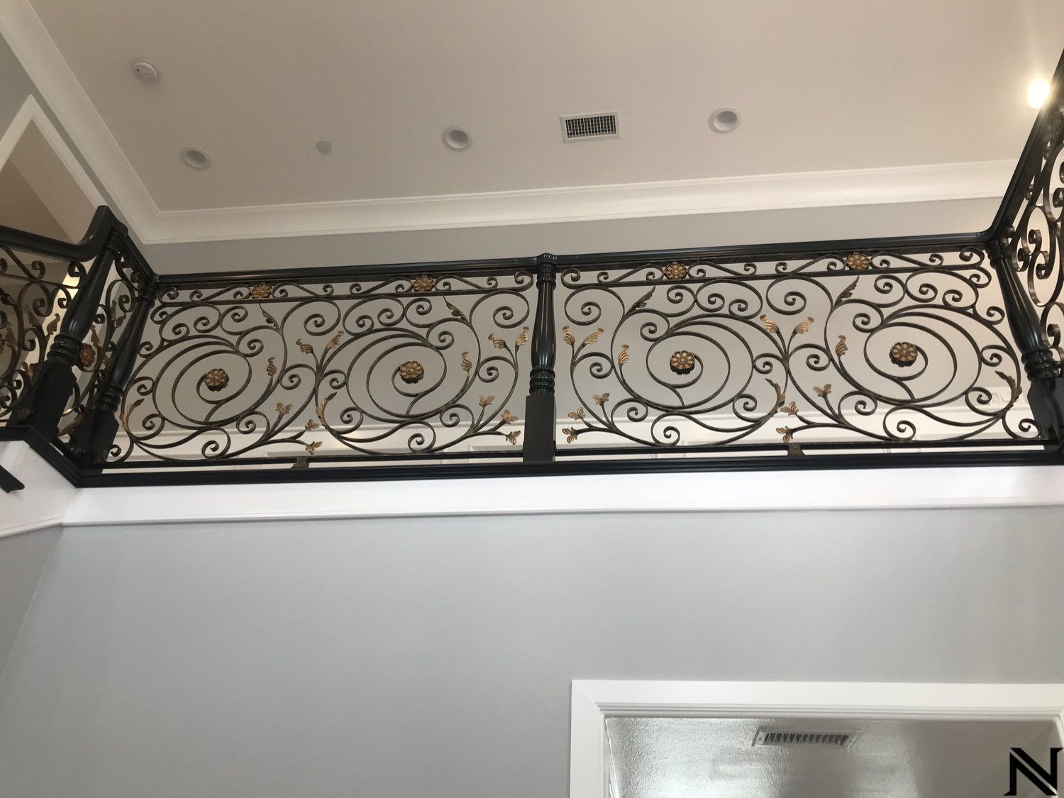 A wrought iron railing is hanging from the ceiling of a room.
