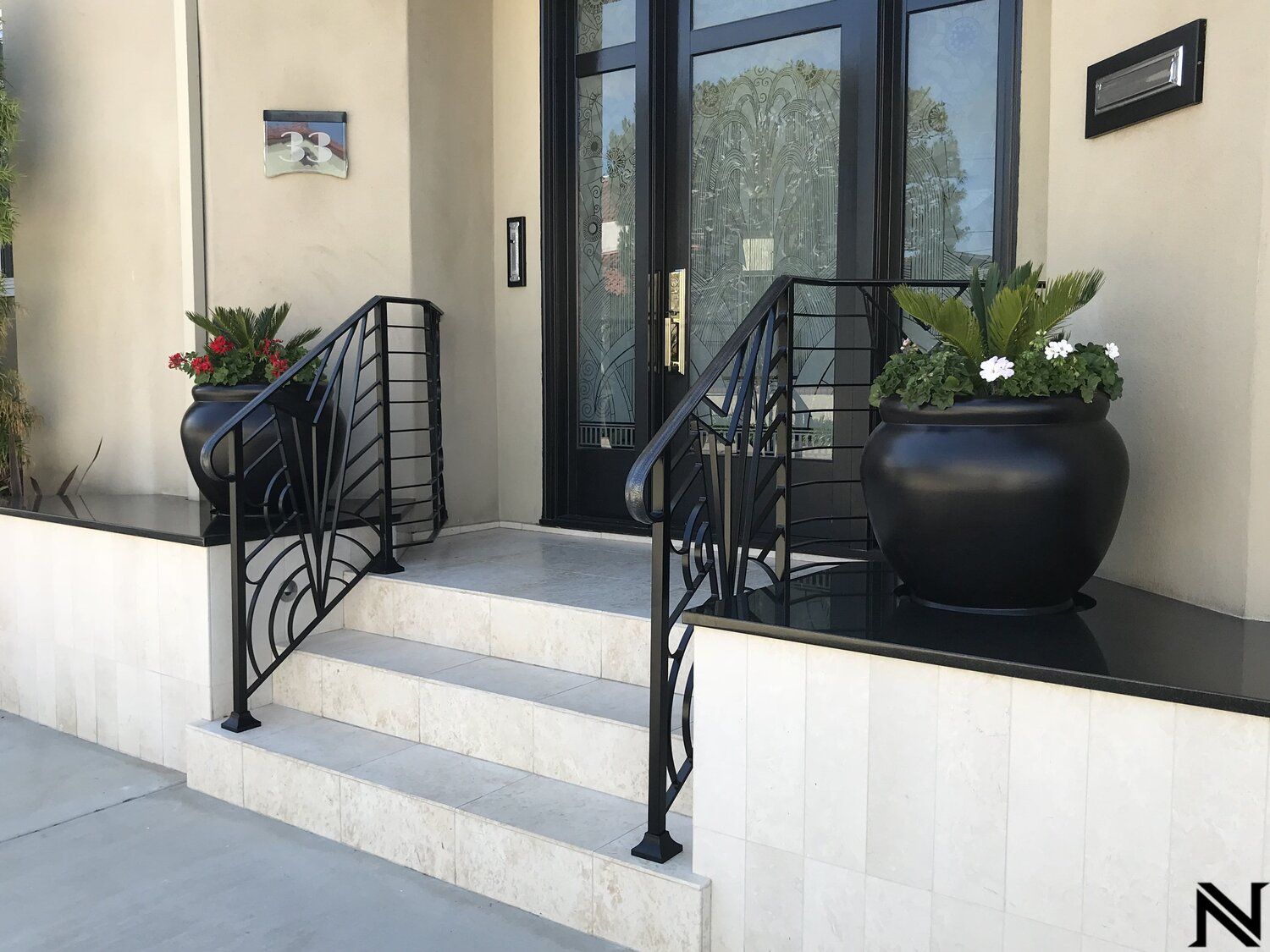 A black potted plant is on the porch of a house.