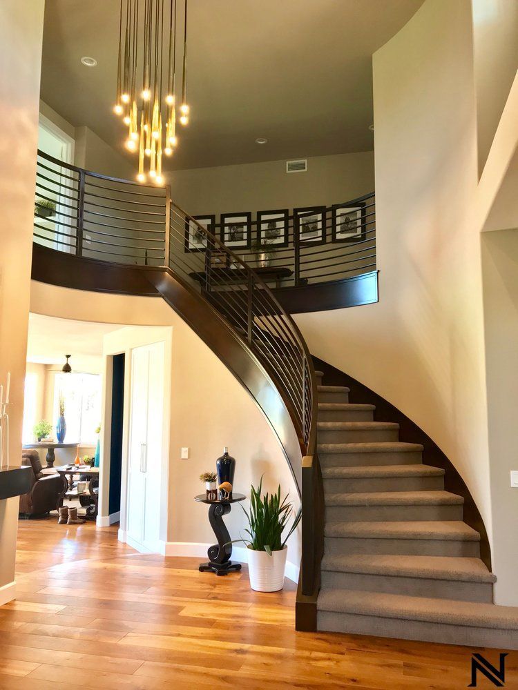 A curved staircase in a house with a chandelier hanging from the ceiling.