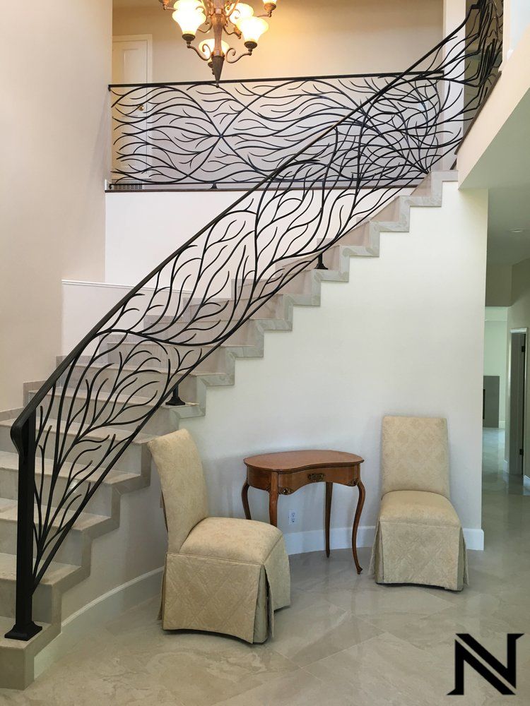 A staircase with a wrought iron railing and chairs