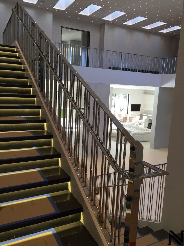 A staircase with a stainless steel railing and lights on the steps