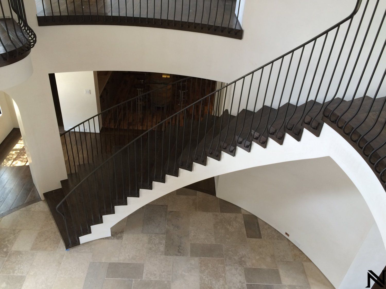 An aerial view of a curved staircase with a wrought iron railing