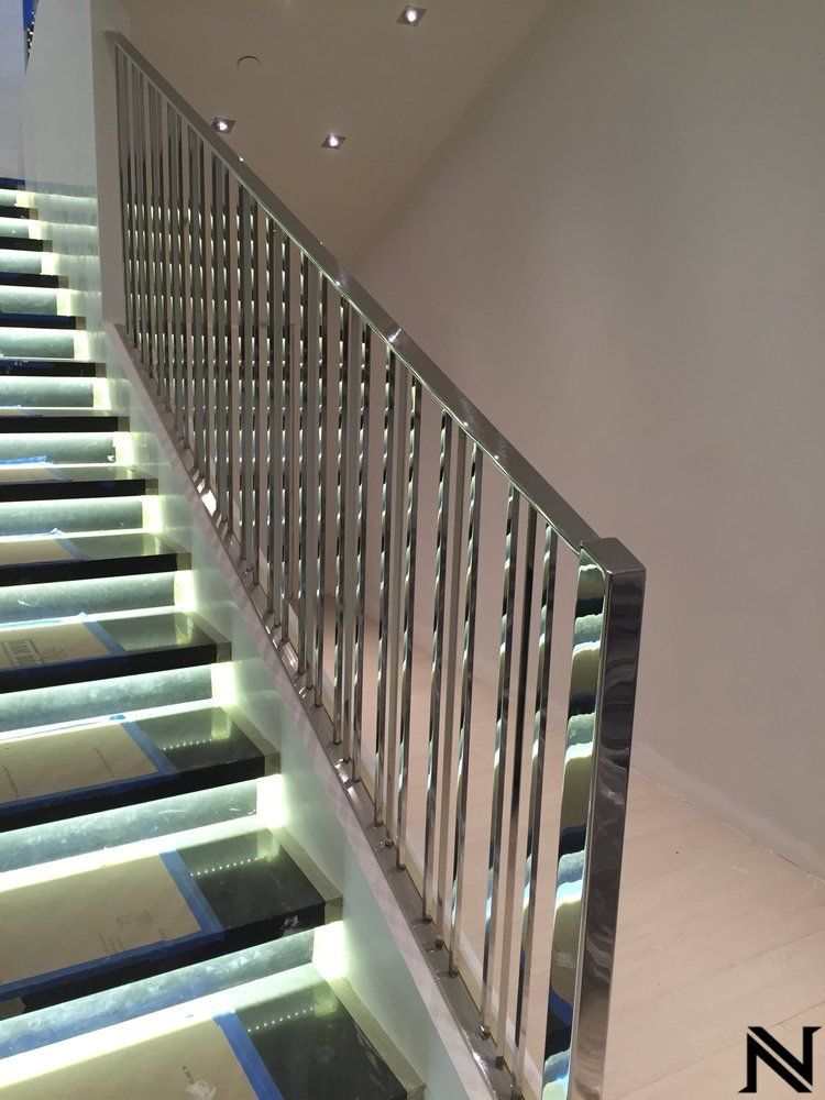 A staircase with a stainless steel railing and the letter n on the bottom
