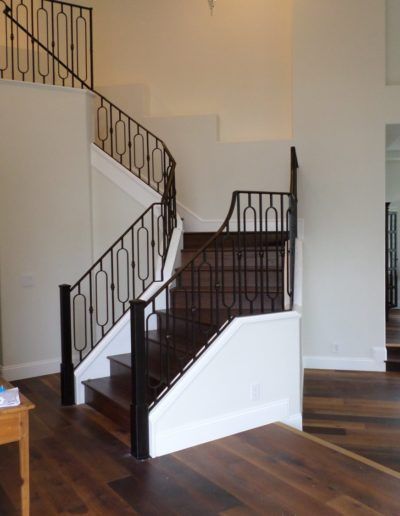 A staircase with a wrought iron railing and a wooden floor
