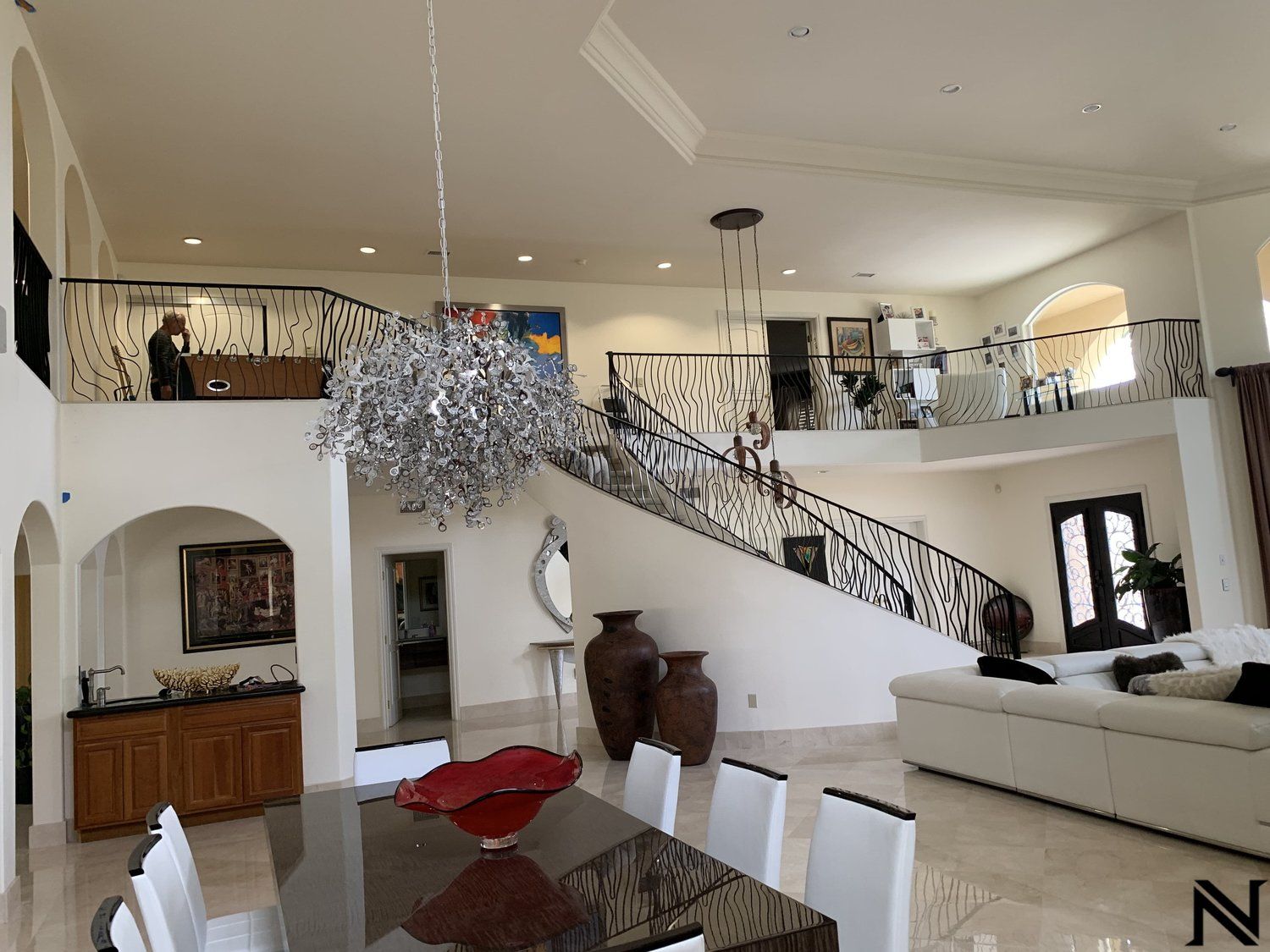 A large living room with a dining table and chairs and stairs leading up to the second floor.
