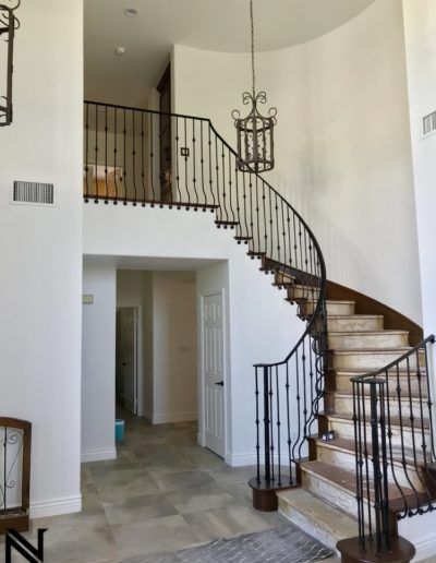A spiral staircase with a wrought iron railing leading up to the second floor