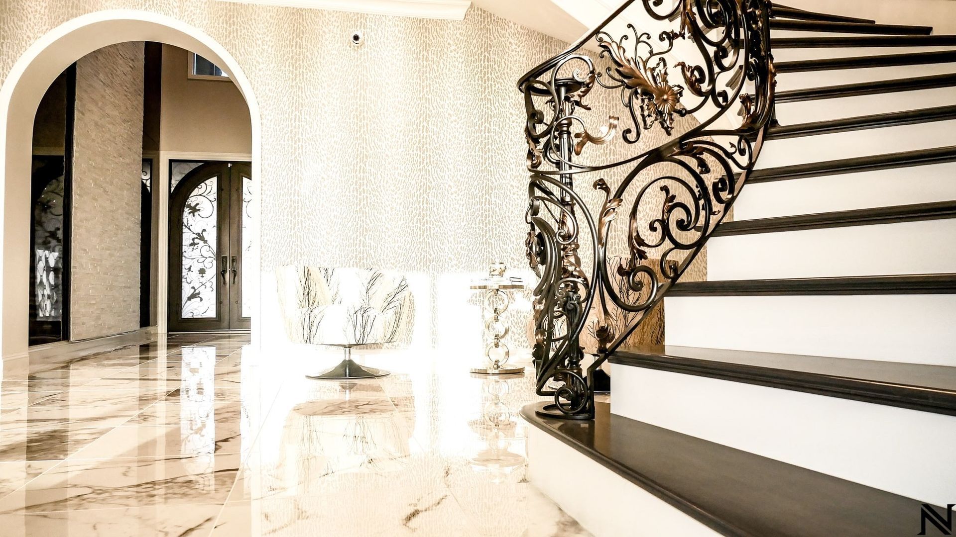 There is a staircase with a wrought iron railing in the middle of the room.