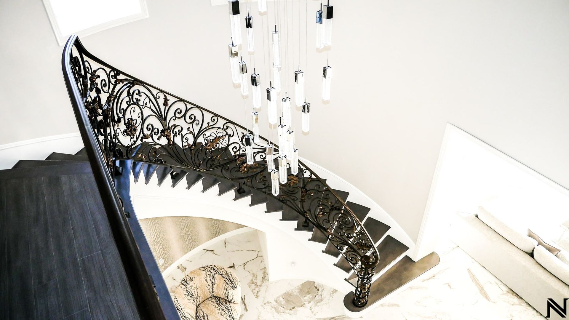 A spiral staircase with a wrought iron railing and a chandelier hanging from the ceiling.
