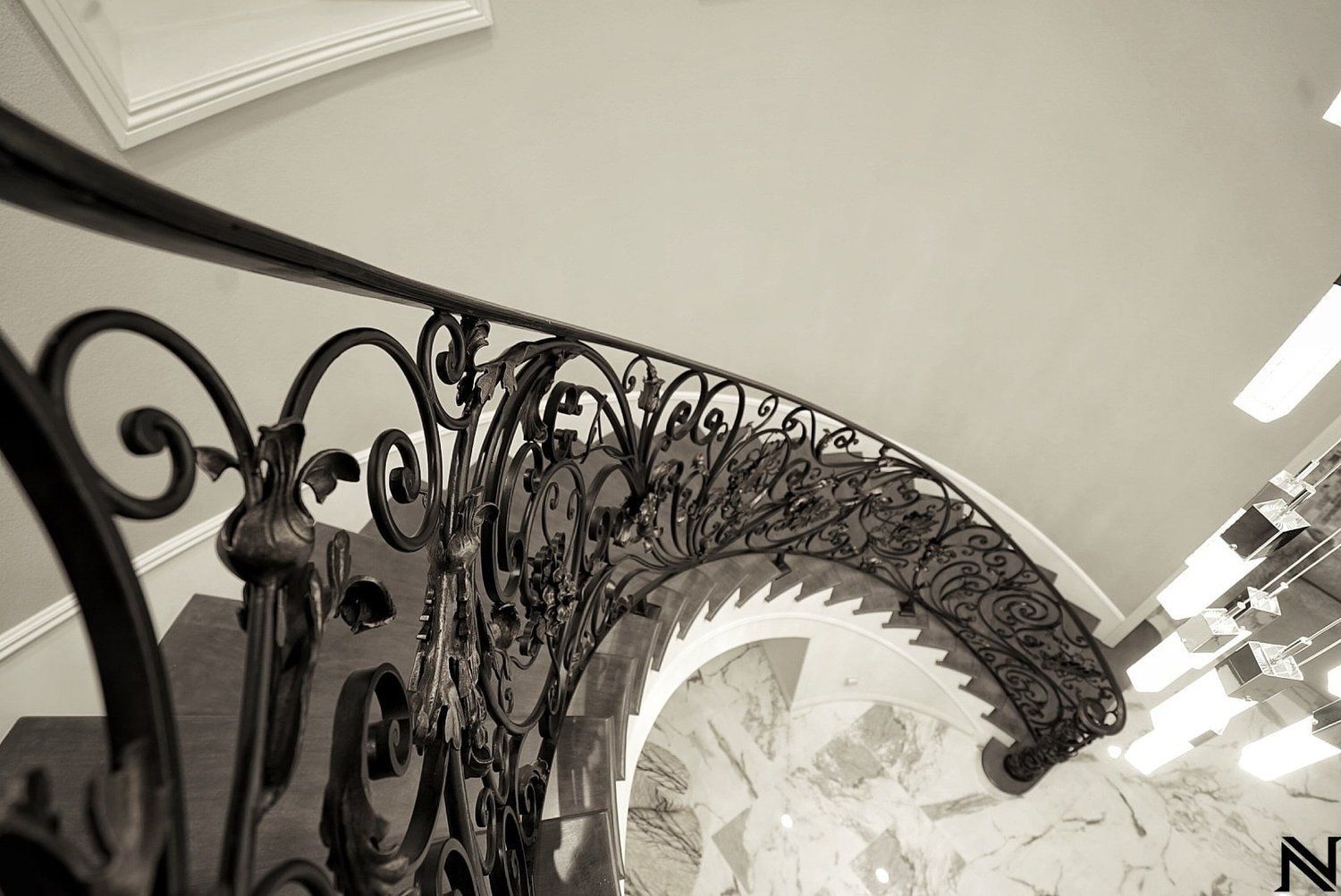 A black and white photo of a spiral staircase with a wrought iron railing.