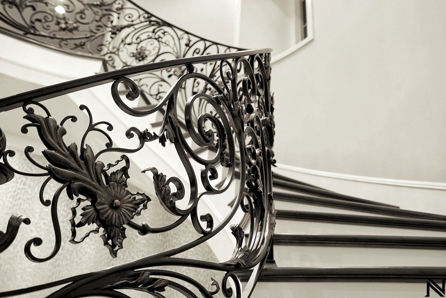 A black and white photo of a wrought iron railing on a spiral staircase.