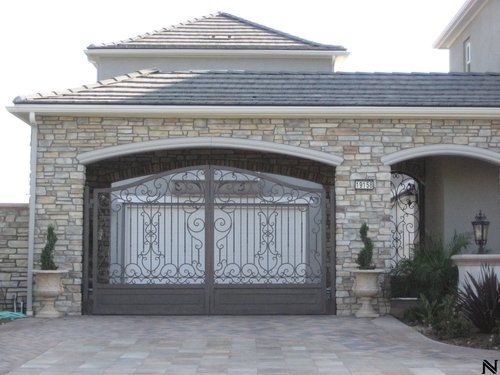A stone house with a wrought iron garage door