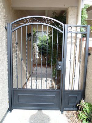 A black wrought iron gate is sitting in front of a house.