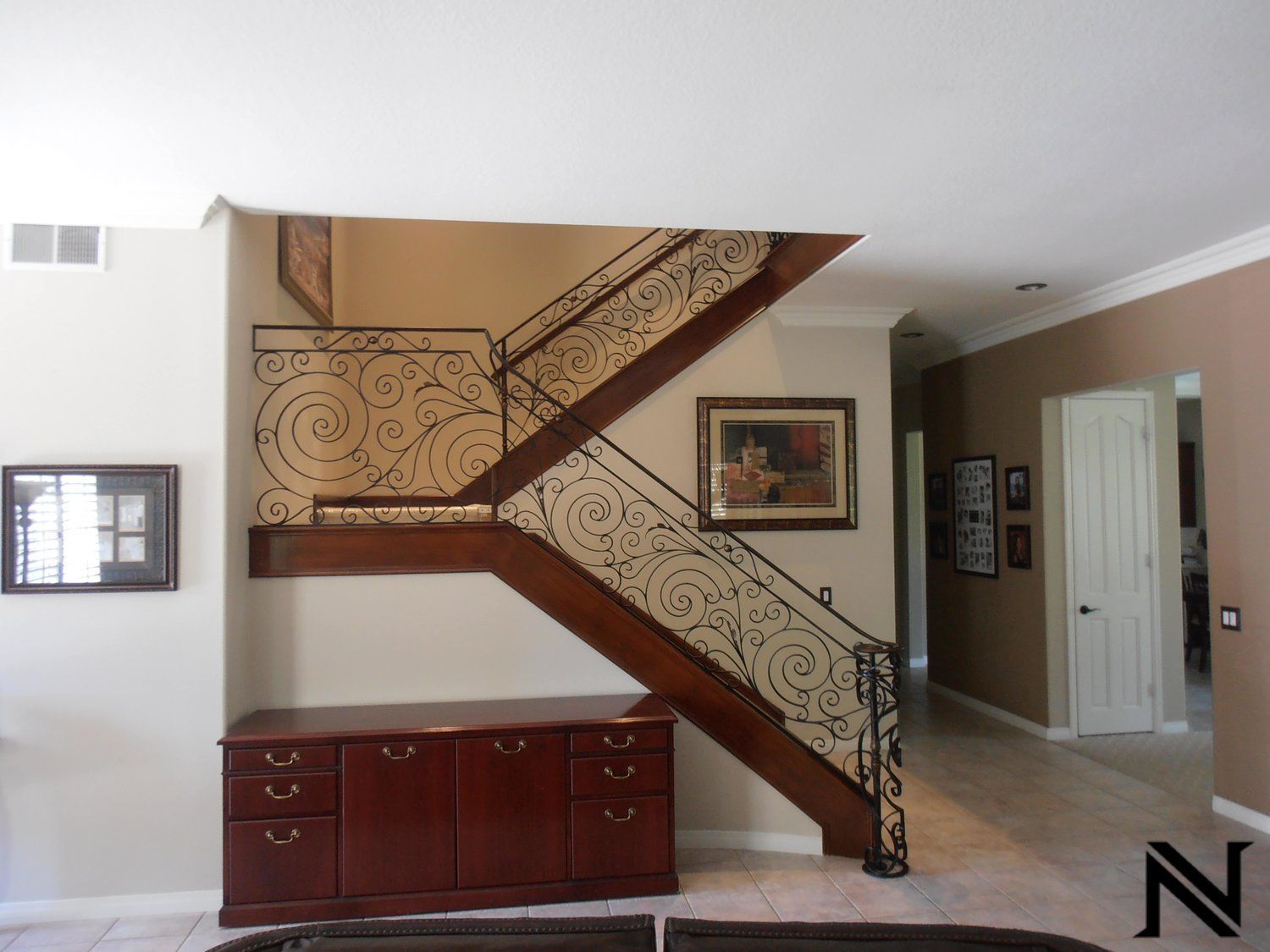 A wooden staircase with a wrought iron railing in a living room