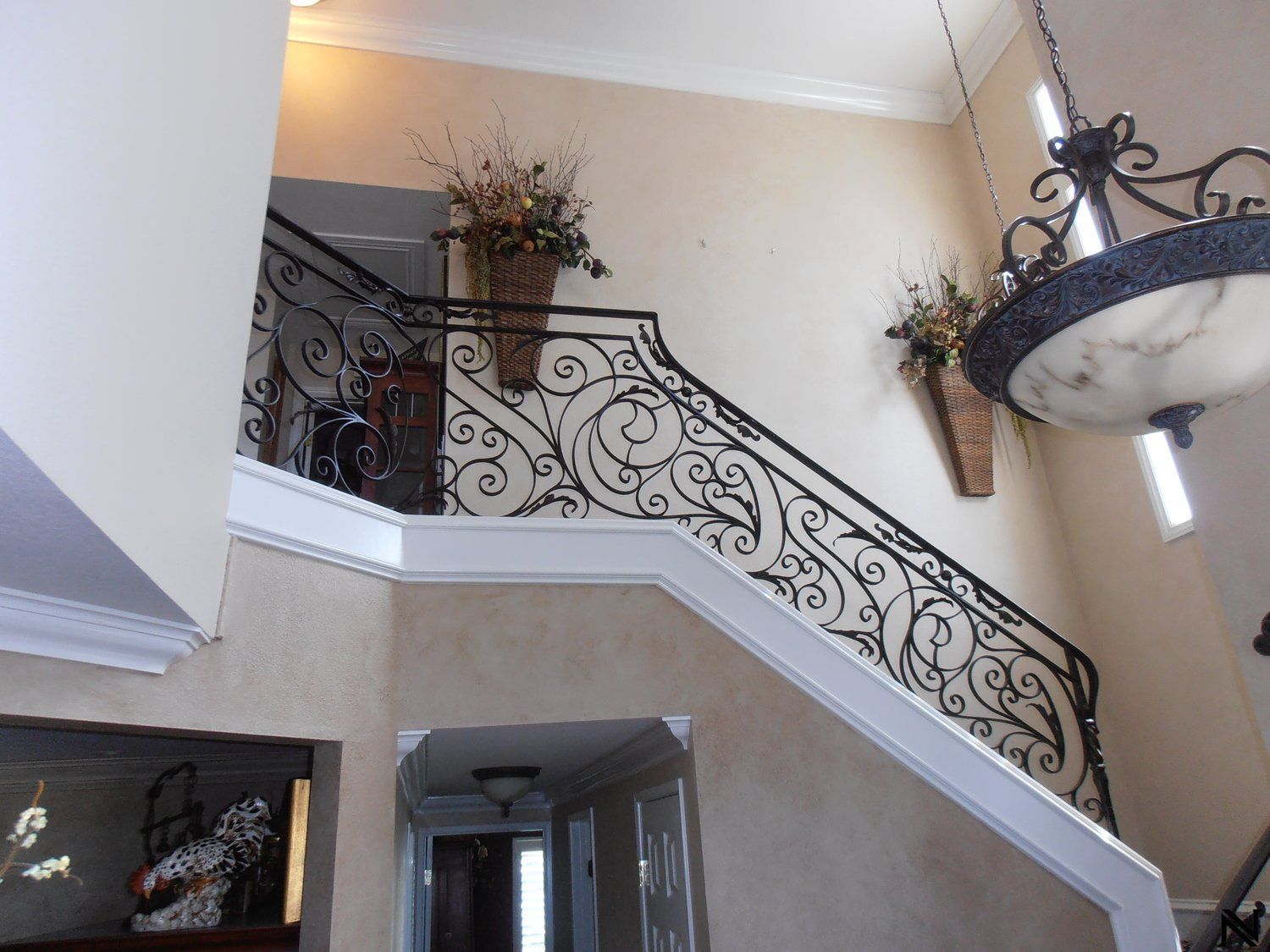 A staircase with a wrought iron railing and a chandelier