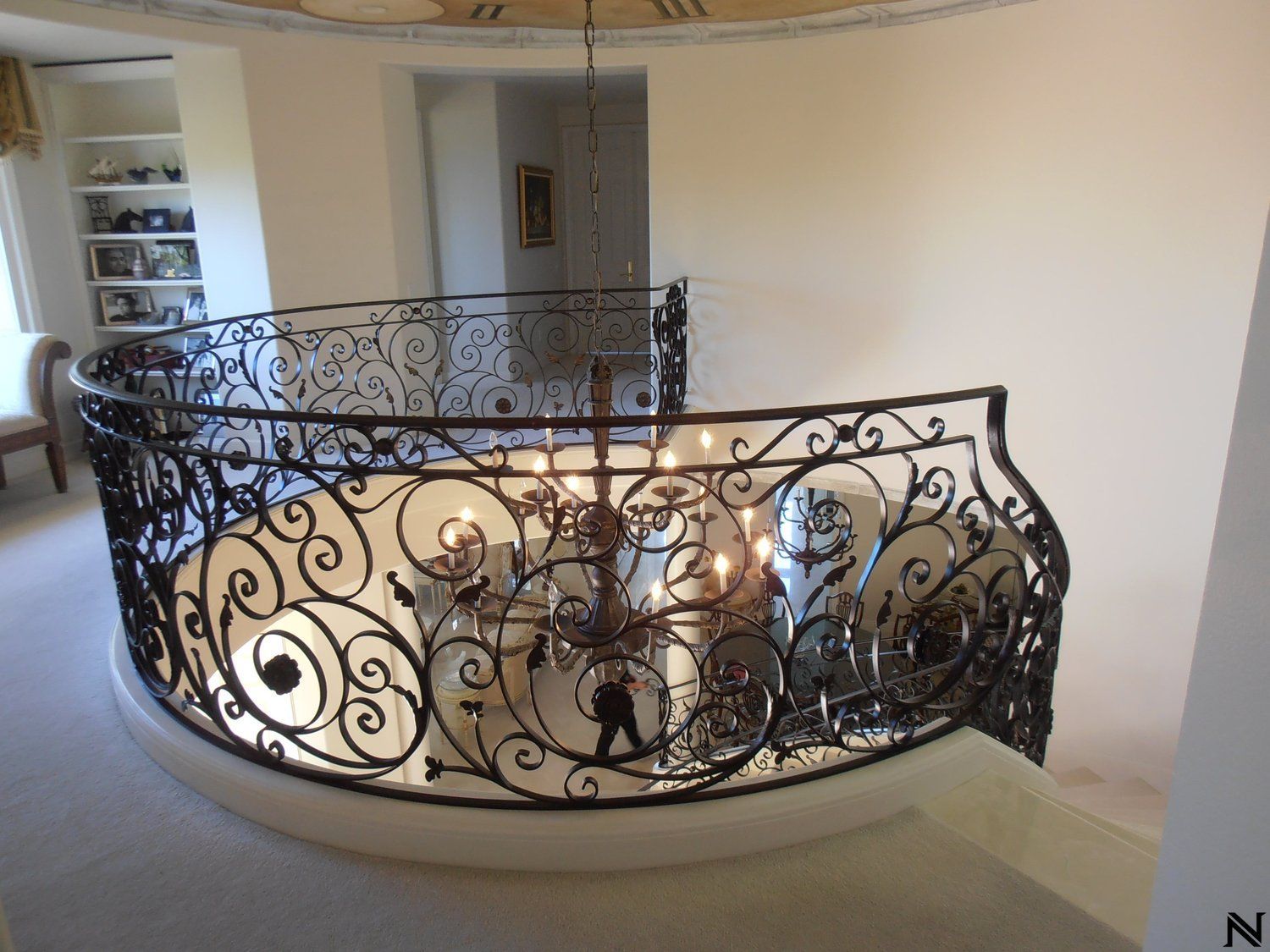 A staircase with a wrought iron railing and a chandelier hanging from the ceiling