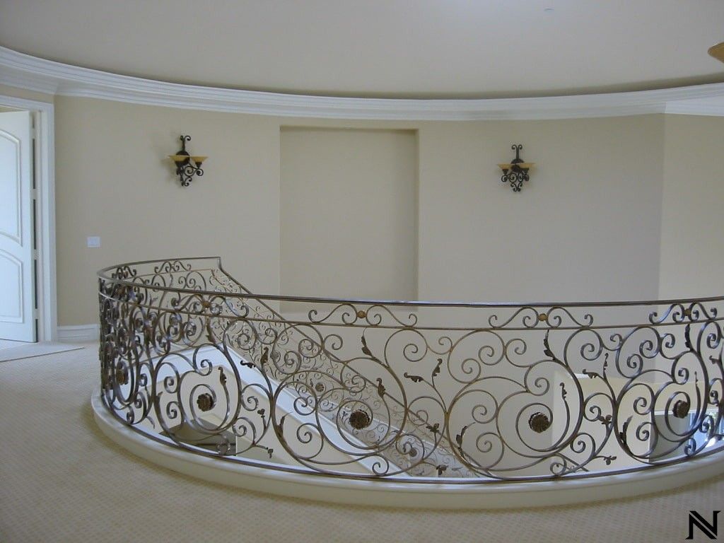 A round staircase with a wrought iron railing and the letter n in the corner