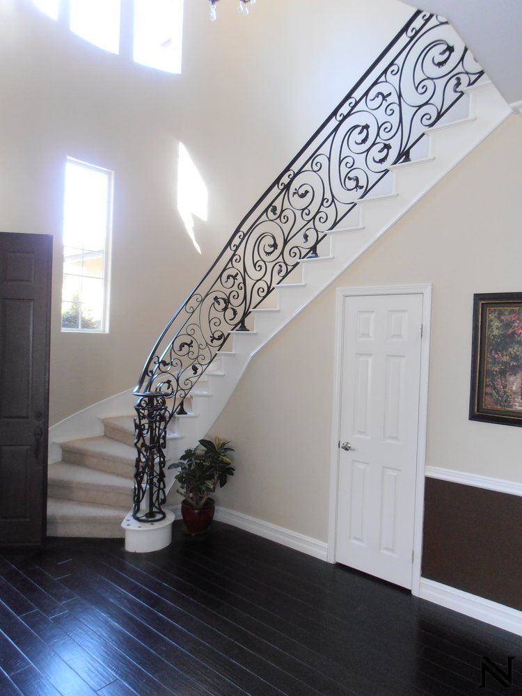 A staircase with a wrought iron railing in a hallway