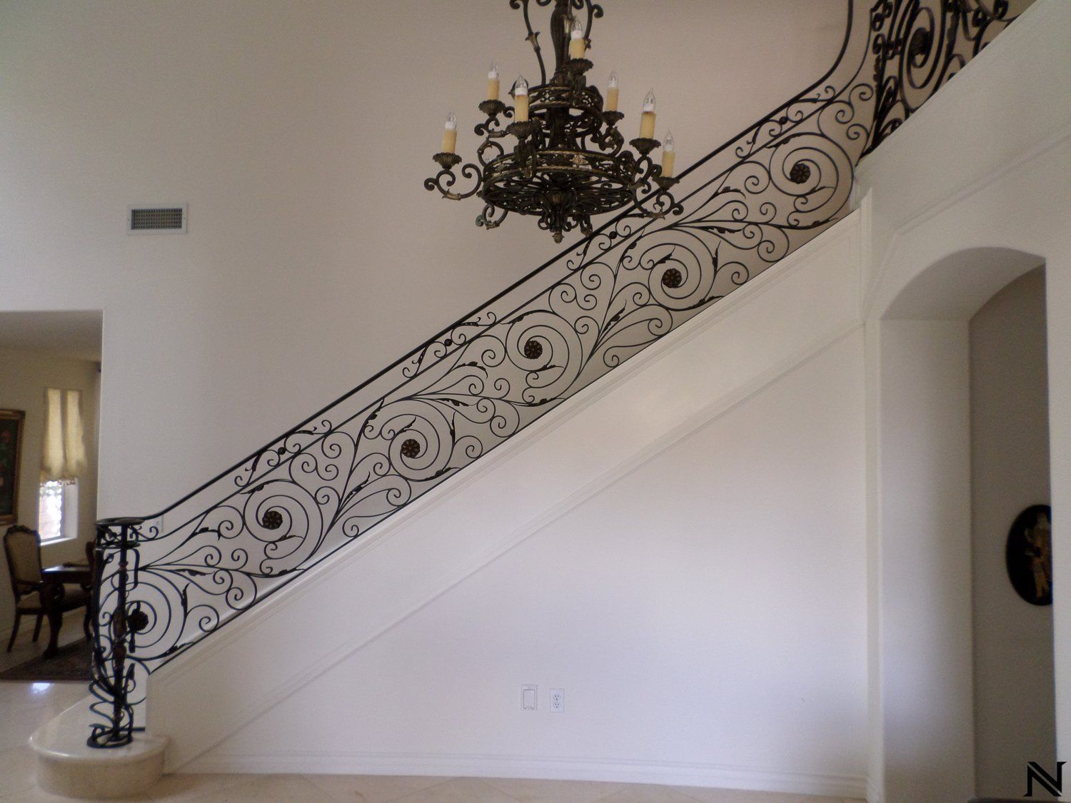 A staircase with a wrought iron railing and a chandelier hanging from the ceiling
