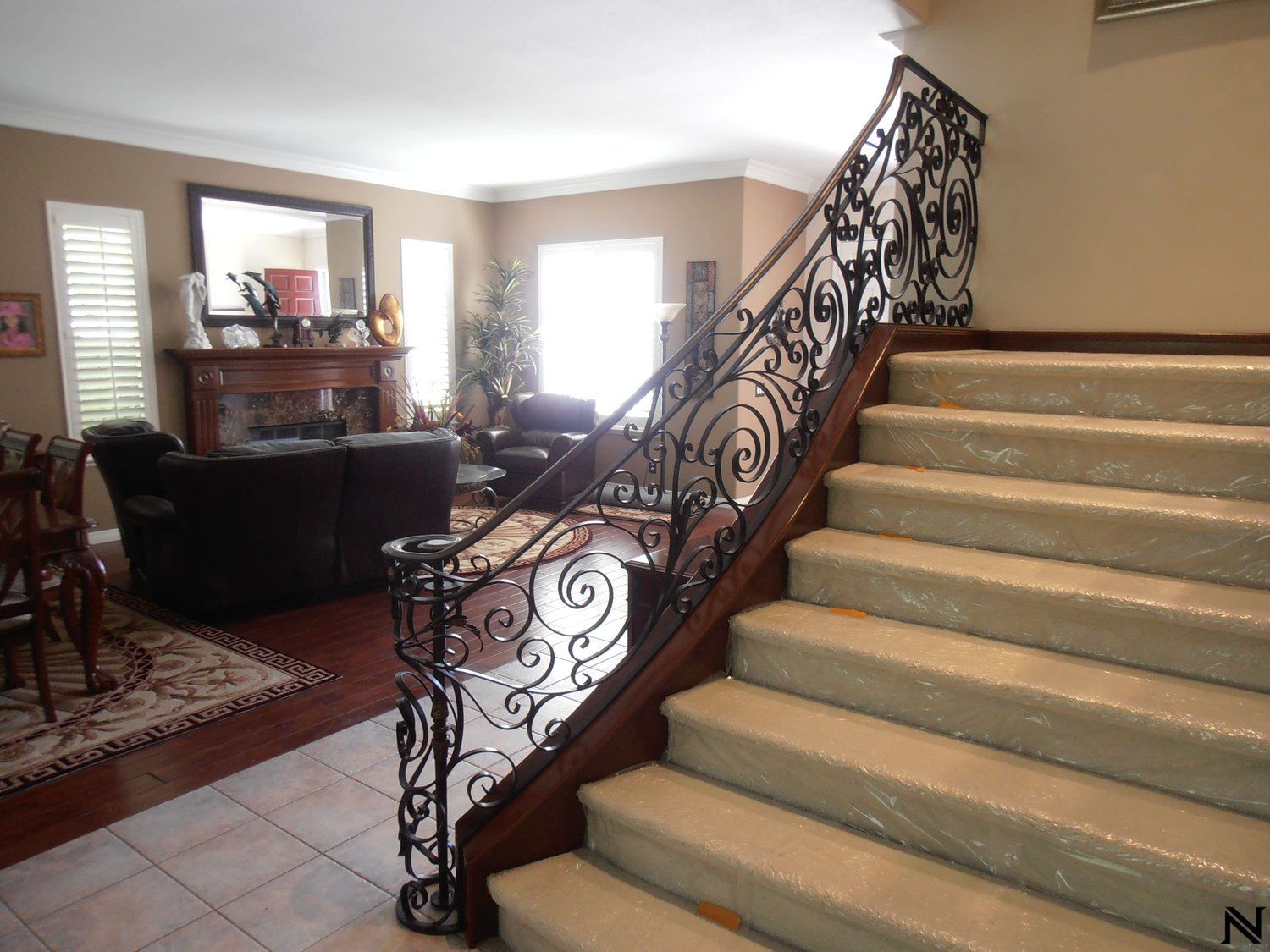 Stairs leading up to a living room with a wrought iron railing