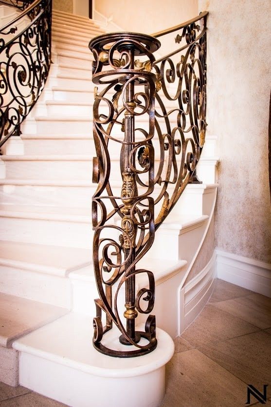 A wrought iron railing surrounds a set of stairs.
