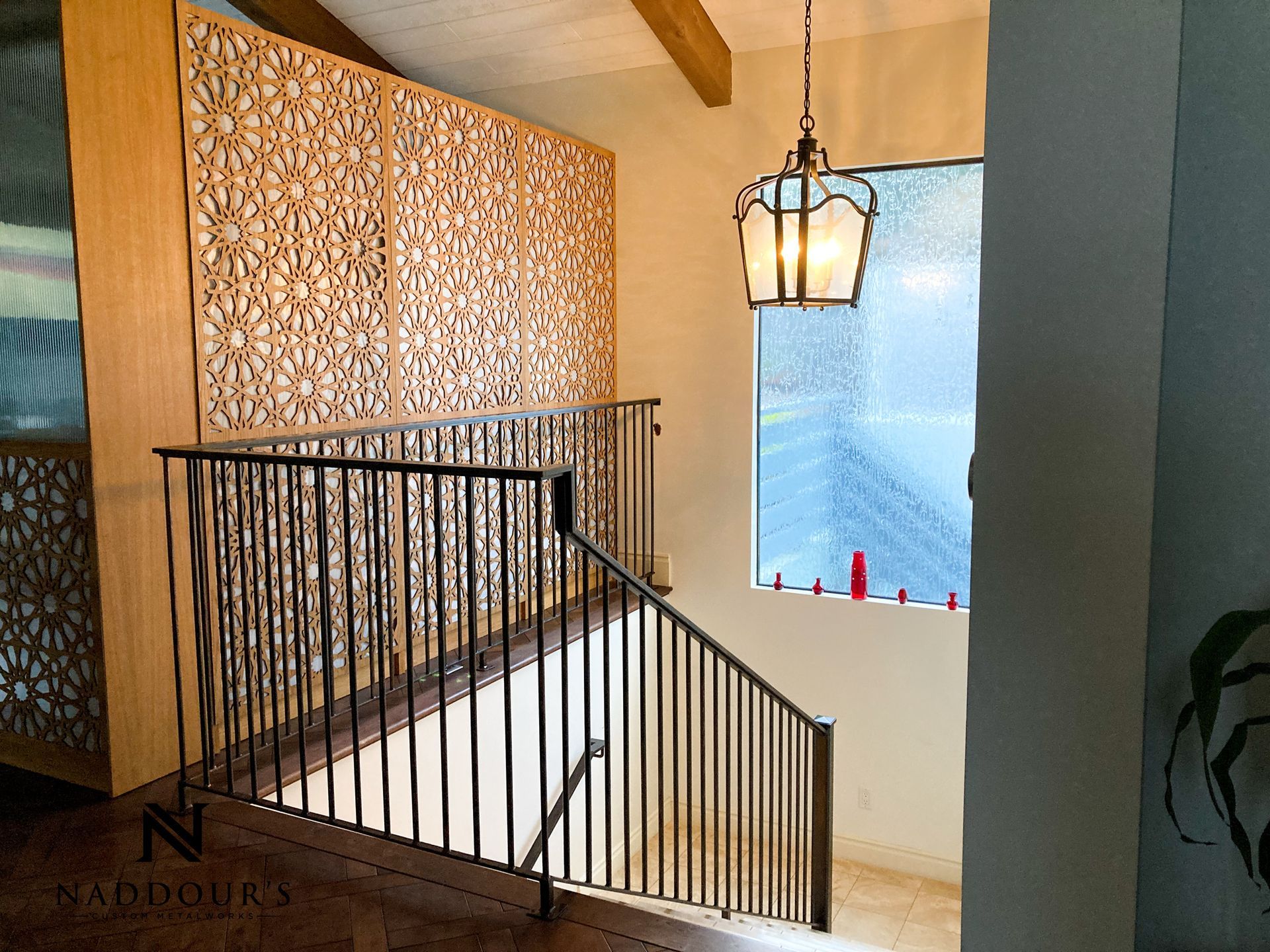 A staircase with a wrought iron railing and a lantern hanging from the ceiling.
